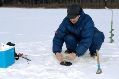 Рыбак зимой на водоеме